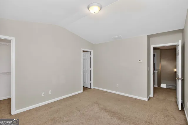 a view of an empty room with closet and a bathroom