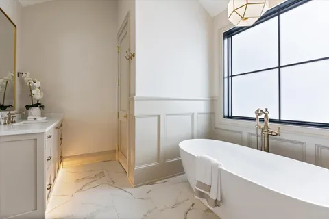 a bathroom with a tub a sink and mirror