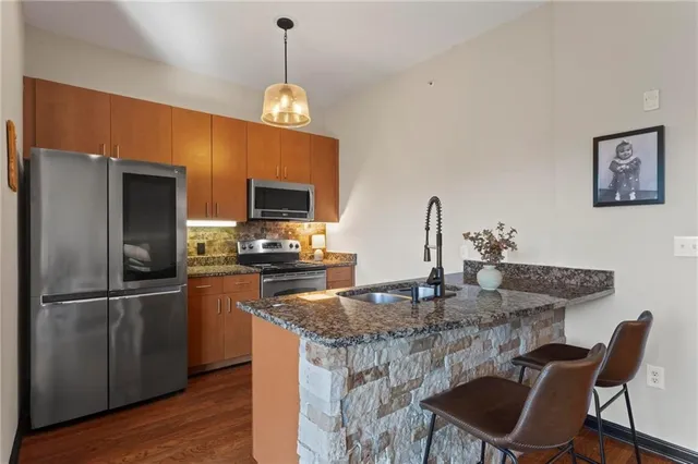 a kitchen with stainless steel appliances granite countertop a sink refrigerator a dining table and chairs