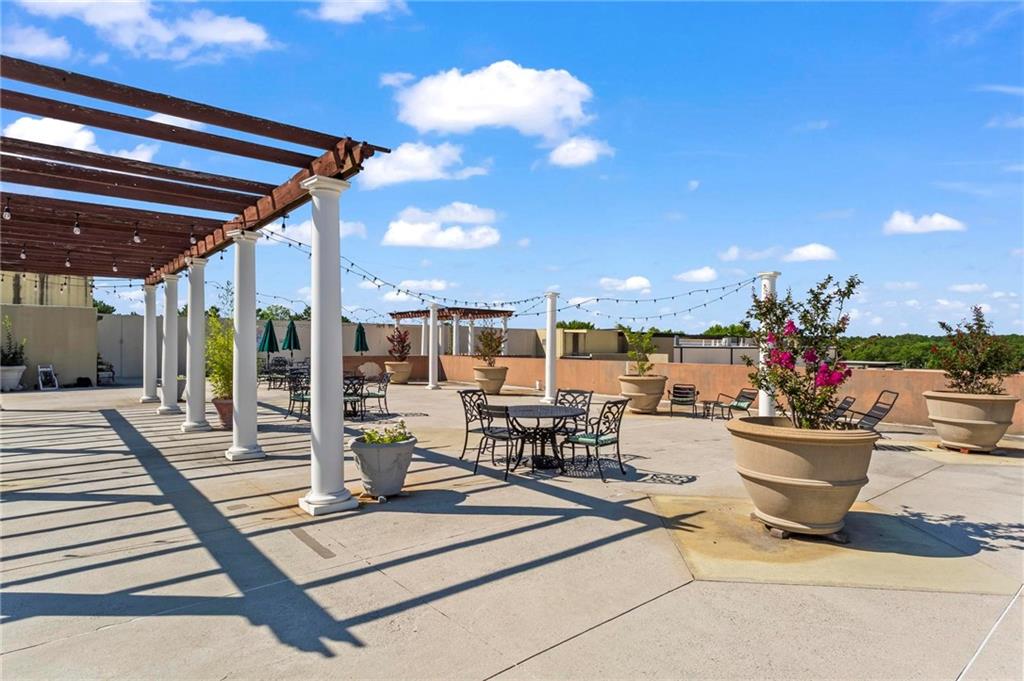 5300 Peachtree Road, Unit 4514 Atlanta, GA 30341 - Photo 27 of 38 a view of a patio with dining table and chairs with potted plants and palm trees
