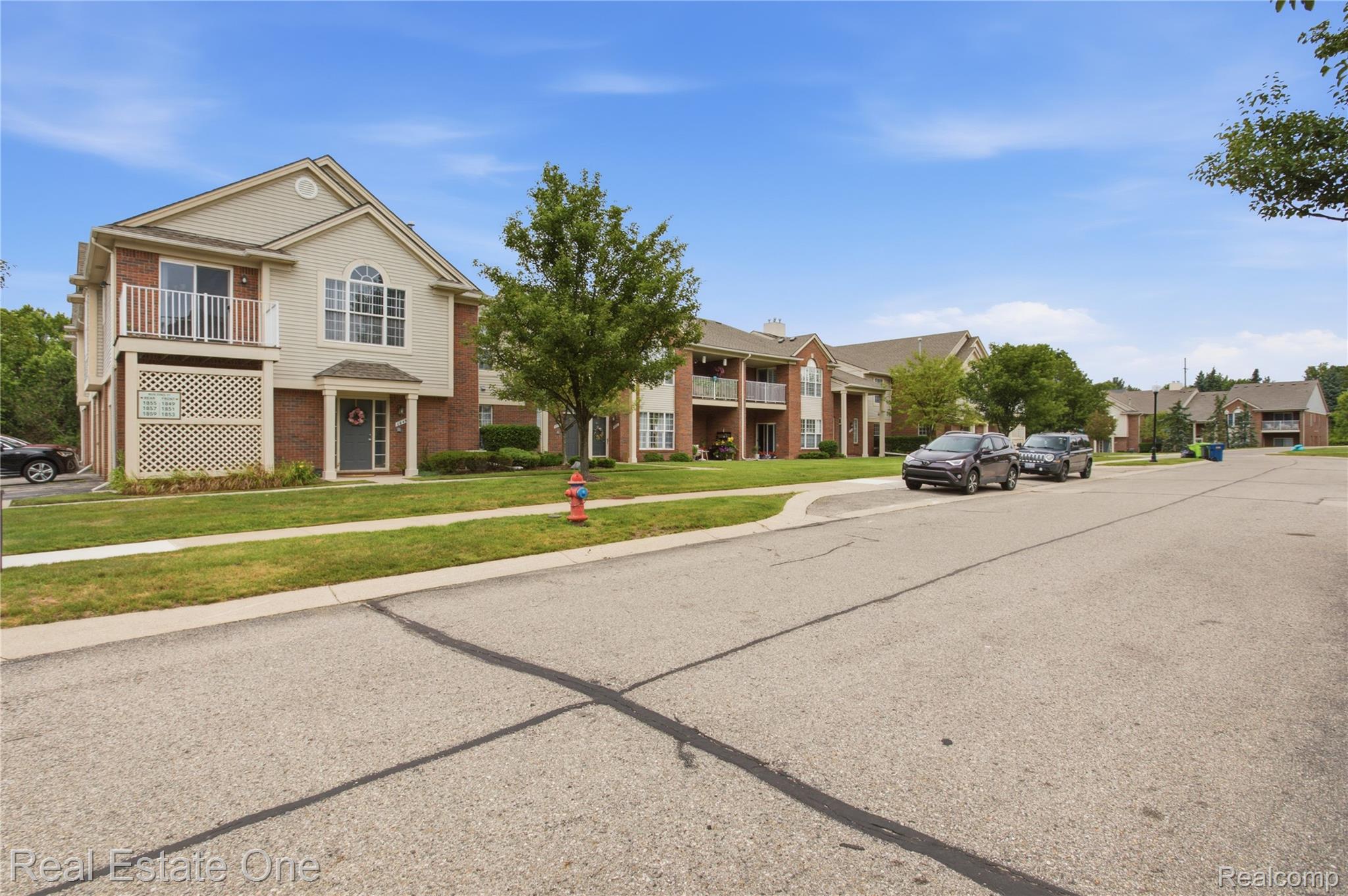 1828 Flagstone Circle, Unit 40 Rochester, MI 48307 - Photo 20 of 22 Brick and siding exterior featuring a balcony, arched window, covered entryway, and manicured landscaping