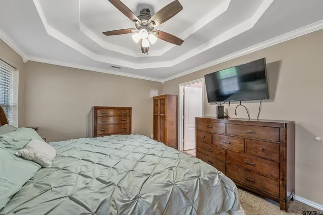 a bedroom with a large bed a flat screen tv and a chandelier