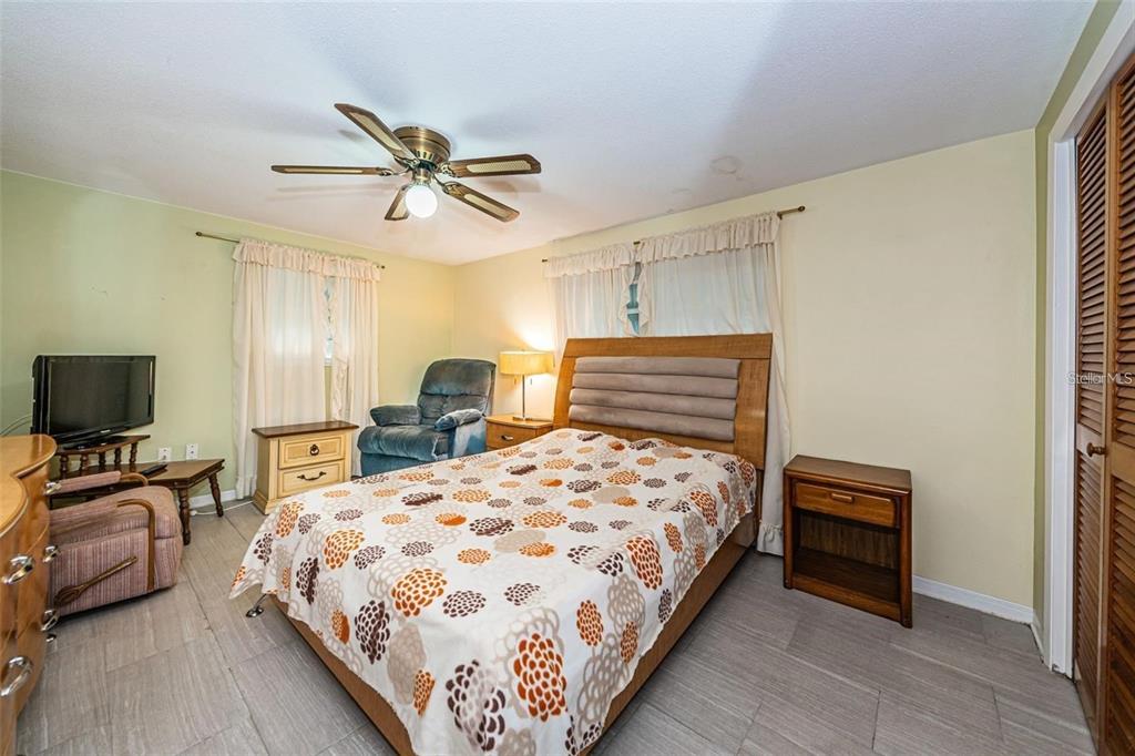 4902 Vision Avenue Holiday, FL 34690 - Photo 15 of 25 a bedroom with a bed a couch and a chandelier