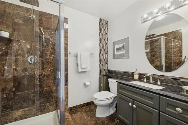 a bathroom with a granite countertop sink toilet and shower
