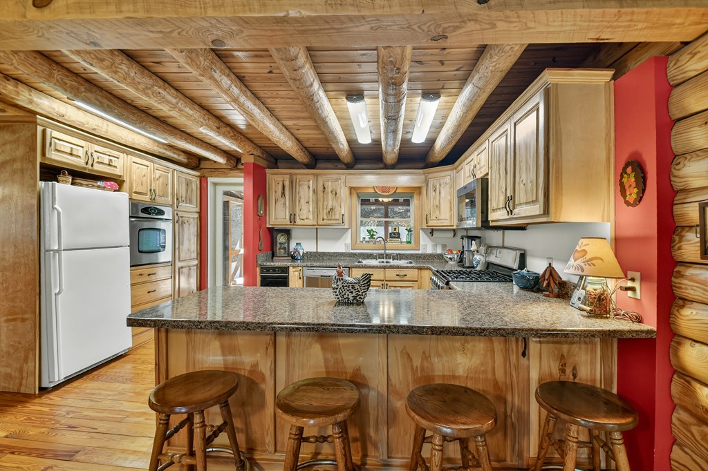 7233 Shakerag Road Ellijay, GA 30540 - Photo 30 of 117 a kitchen with stainless steel appliances granite countertop a table chairs sink refrigerator and microwave