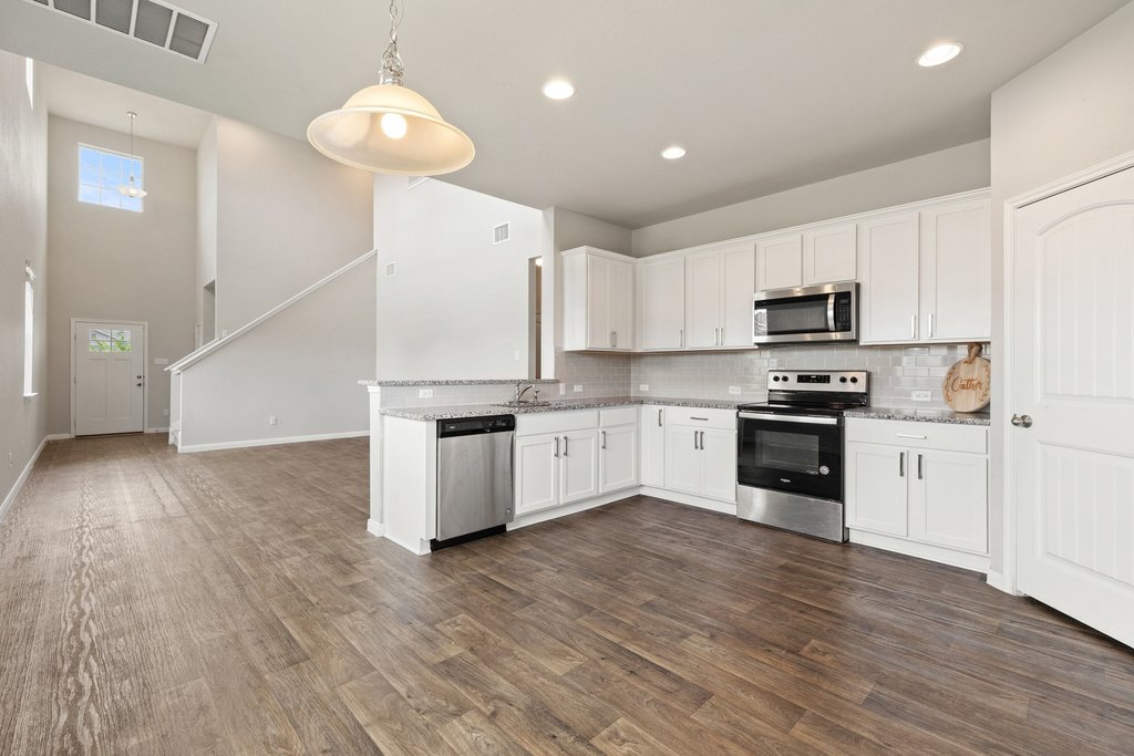 102 Ashford Way Georgetown, TX 78626 - Photo 11 of 28 A well-lit kitchen with sleek stainless steel appliances flows into a bright entry with high ceilings.