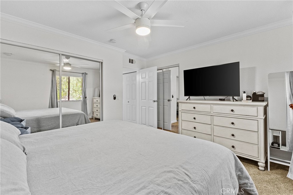 10151 Arrow Route, Unit 6 Rancho Cucamonga, CA 91730 - Photo 9 of 24 a bedroom with a bed a flat screen tv and a chandelier