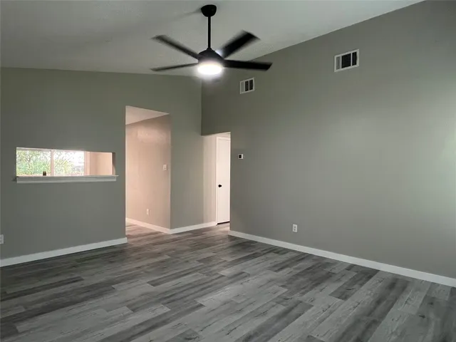 an empty room with wooden floor chandelier fan and closet area