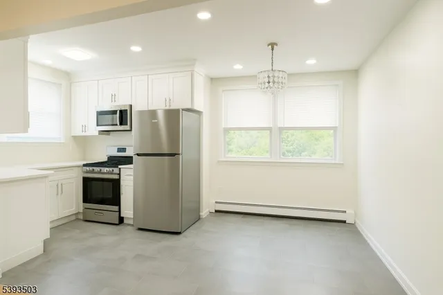 a kitchen with refrigerator a stove and white cabinets