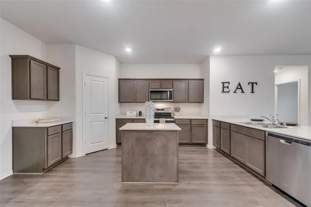 a large kitchen with cabinets wooden floor and stainless steel appliances