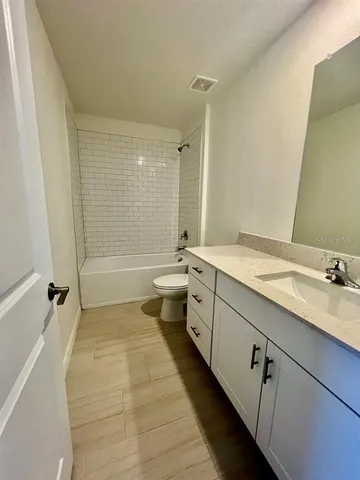 a bathroom with a double vanity sink toilet mirror and bathtub
