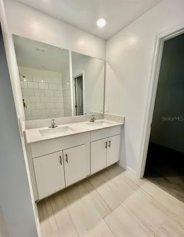 a spacious bathroom with a double vanity sink a mirror and a shower