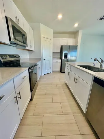 a kitchen with stainless steel appliances a sink dishwasher stove refrigerator and microwave