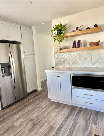 a kitchen with granite countertop white cabinets and refrigerator
