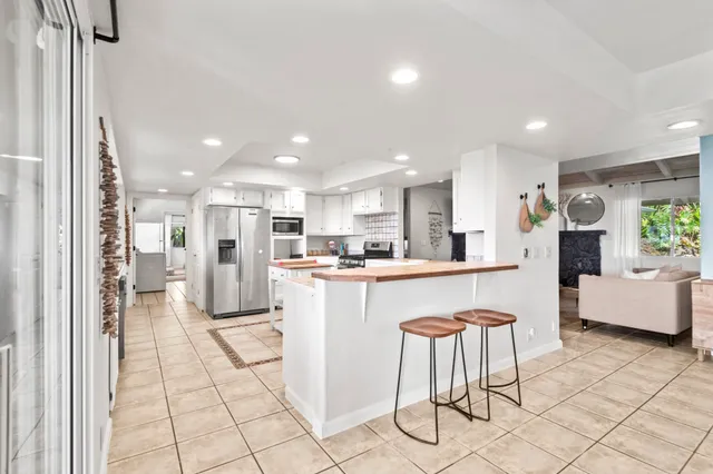 a kitchen with stainless steel appliances kitchen island granite countertop a refrigerator and a sink