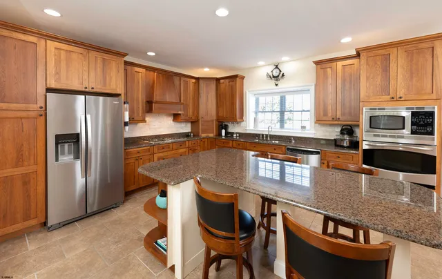 a kitchen with granite countertop stainless steel appliances a refrigerator and cabinets