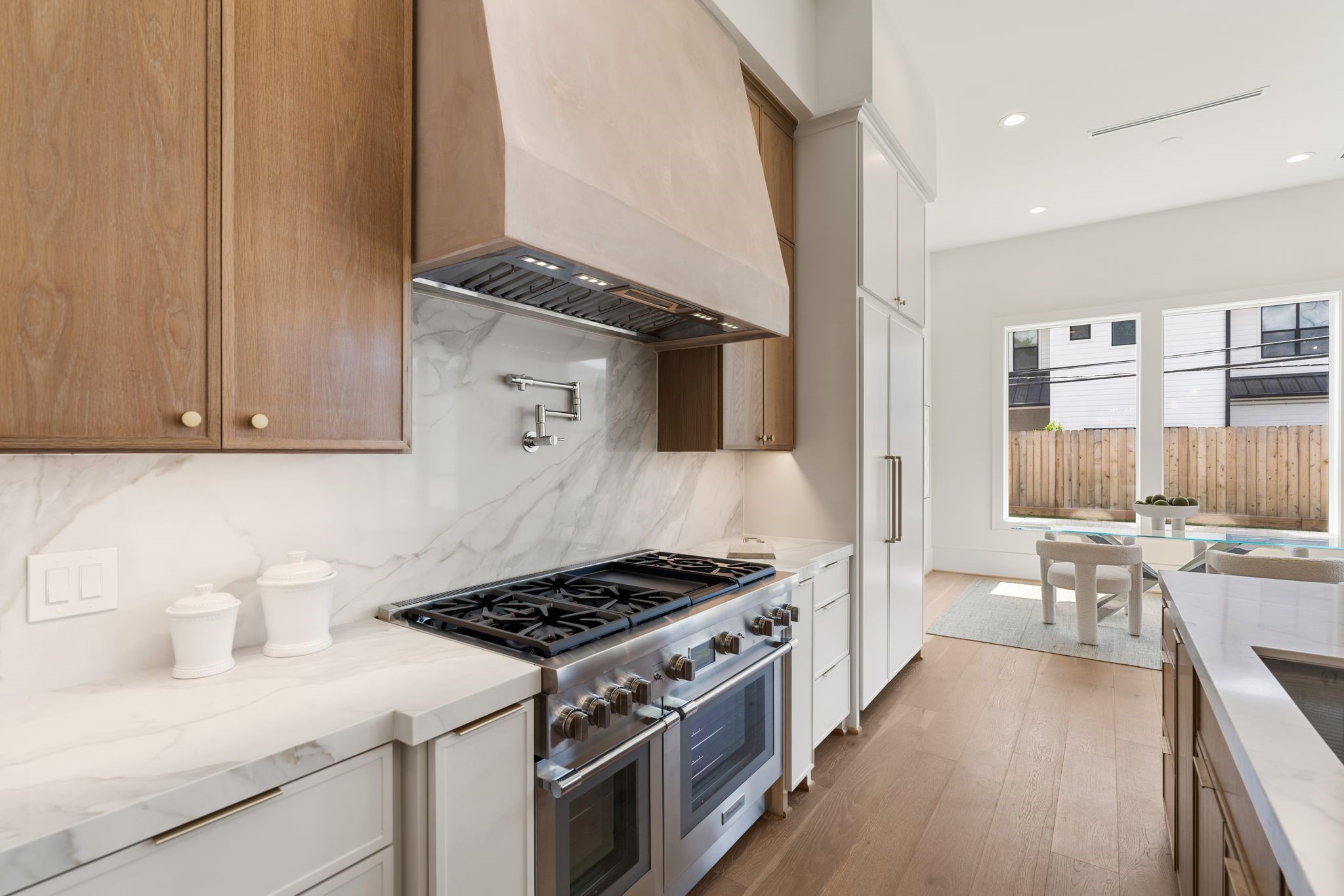 1407 Martin Street Houston, TX 77018 - Photo 18 of 44 A professional-grade range is framed by a custom plaster vent hood, flanked by white oak cabinetry and a full-height quartzite backsplash, blending performance with refined design.