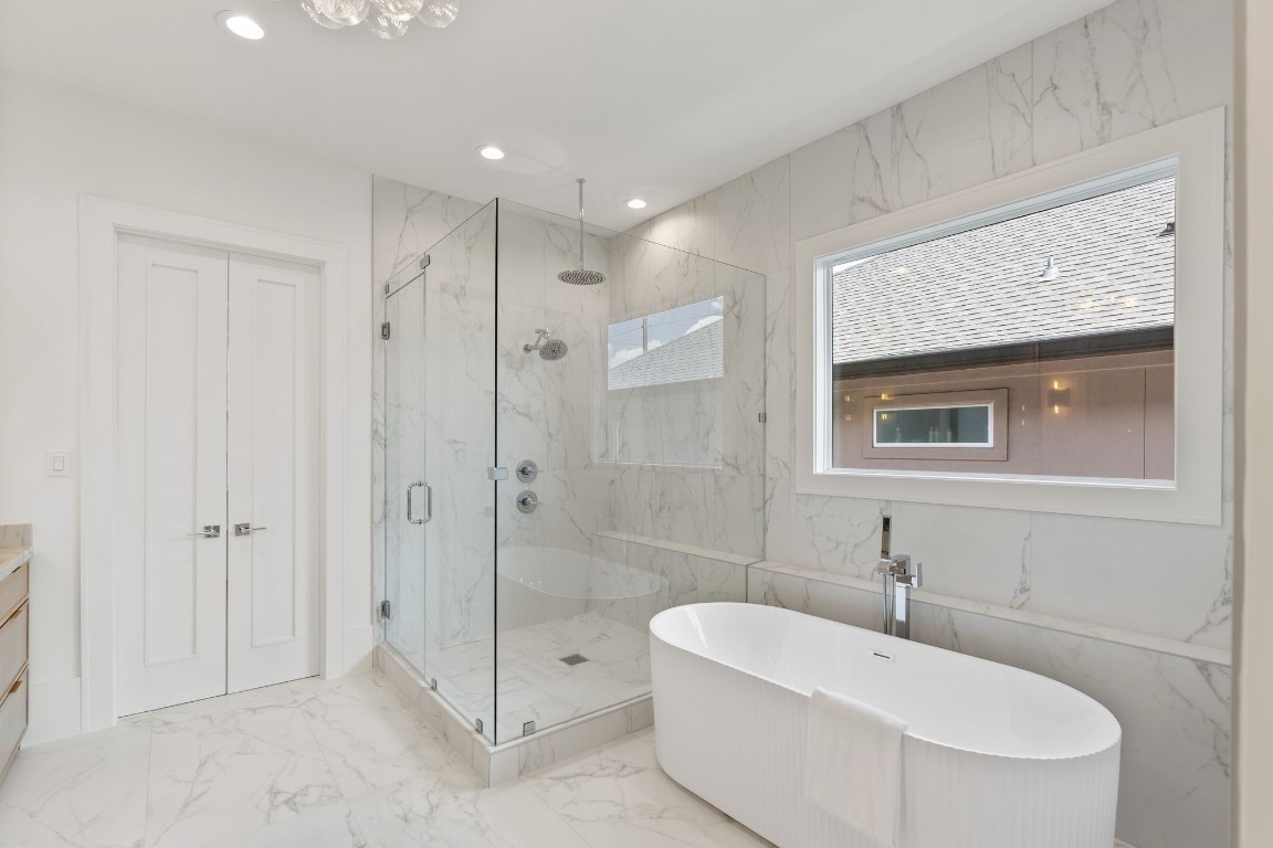 1407 Martin Street Houston, TX 77018 - Photo 35 of 44 A glass-enclosed walk-in shower with full-height marble tile sits alongside a freestanding soaking tub, offering a true retreat-like experience.