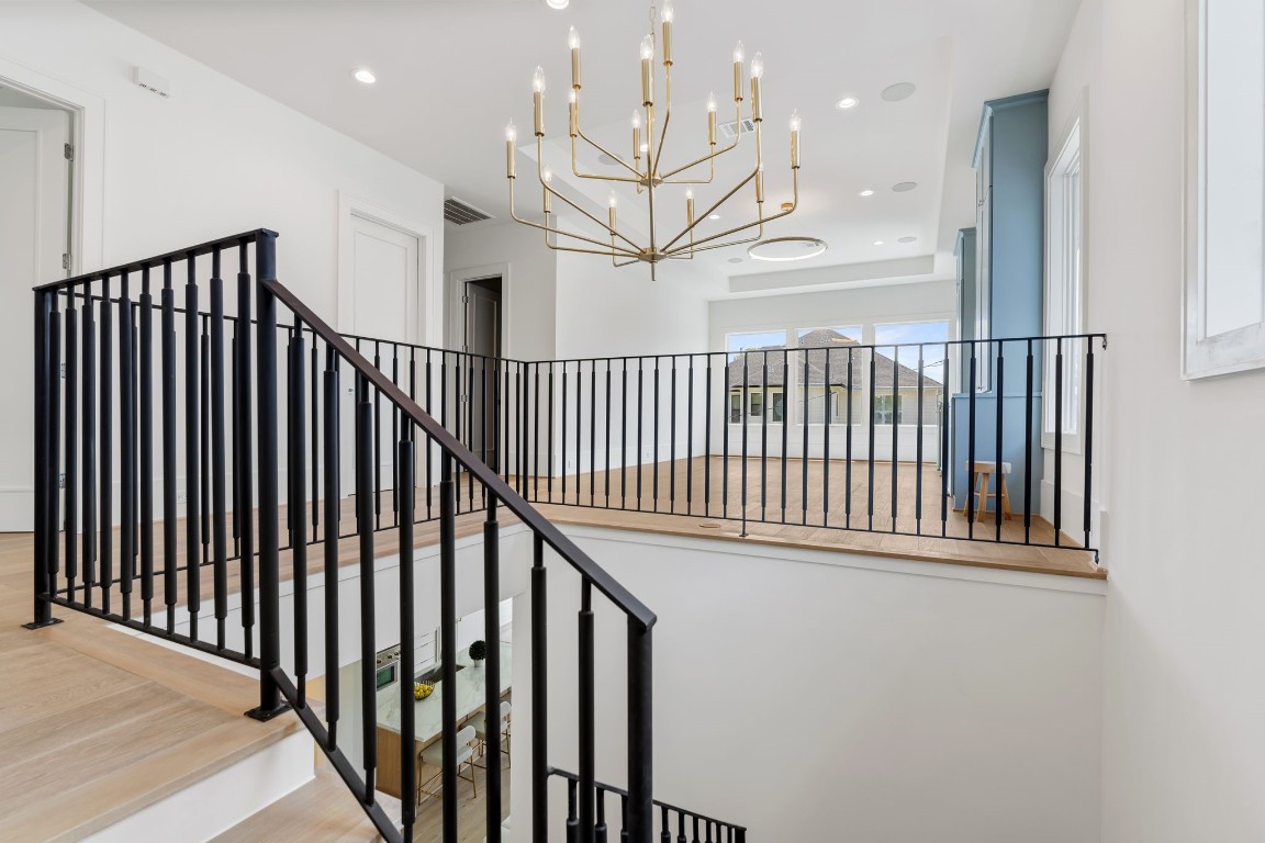 1407 Martin Street Houston, TX 77018 - Photo 41 of 44 The upstairs landing overlooks the main living area below, featuring modern iron railings and a statement chandelier that enhances the home’s open, airy feel.