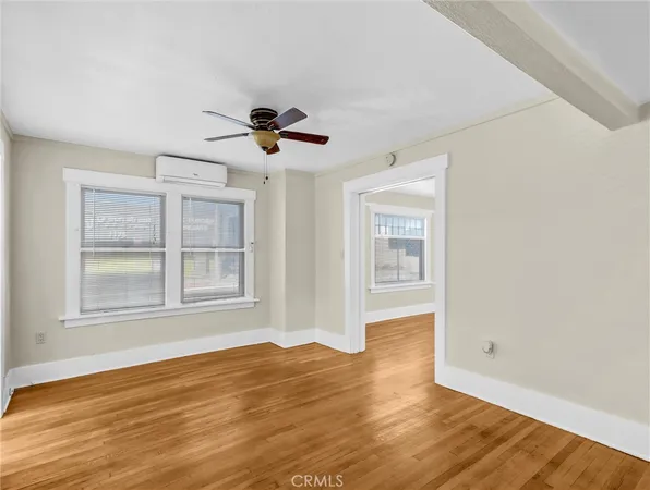 a view of an empty room with a window and wooden floor