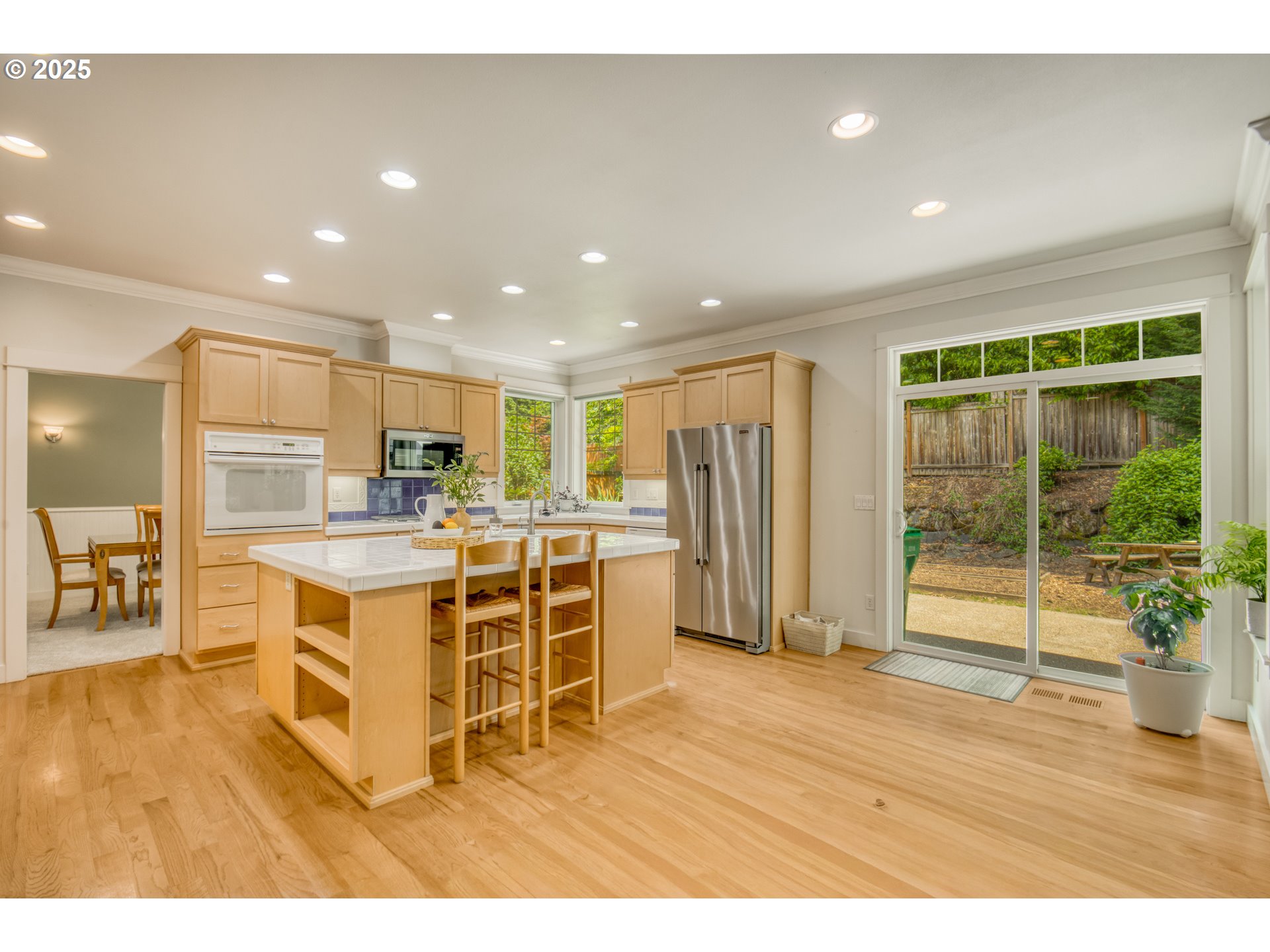 11540 Southwest 58th Court Portland, OR 97219 - Photo 11 of 33 a kitchen with stainless steel appliances kitchen island granite countertop a refrigerator a sink a stove and white cabinets with wooden floor