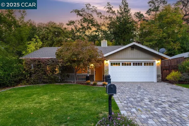 a view of a house with a yard and large tree
