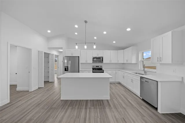 a large kitchen with stainless steel appliances kitchen island a large counter top and a stove top oven