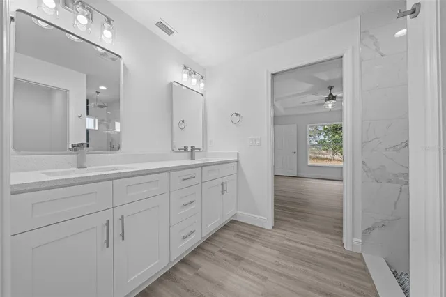 a spacious bathroom with double vanity a mirror and shower