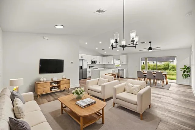 a living room with furniture a flat screen tv and kitchen view