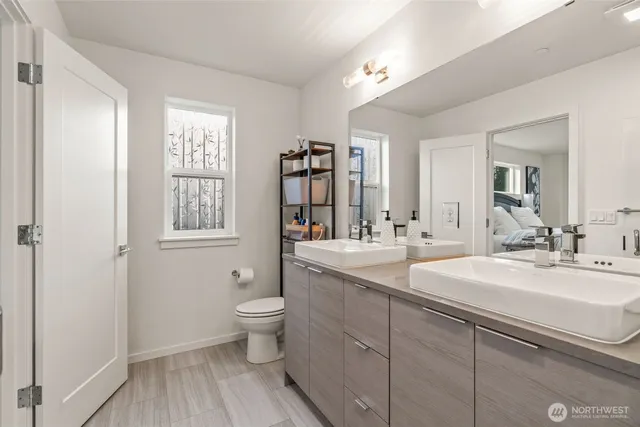 a spacious bathroom with a double vanity sink a large mirror and a toilet
