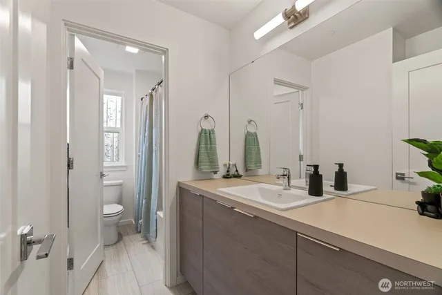 a bathroom with a double vanity sink toilet and a tub