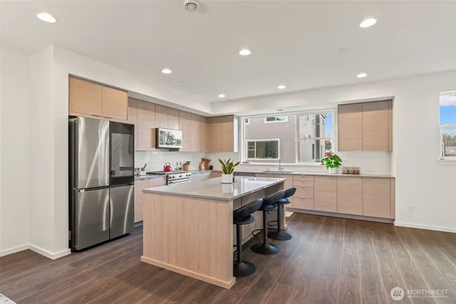 a kitchen with stainless steel appliances granite countertop a refrigerator a stove and a wooden floors