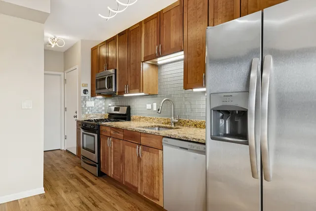 a kitchen with stainless steel appliances granite countertop a stove a sink and a refrigerator