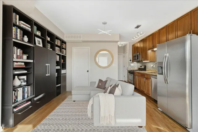a living room with stainless steel appliances furniture a rug and a window