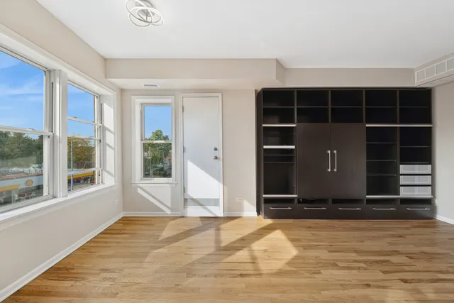 a view of an empty room with a window and wooden floor
