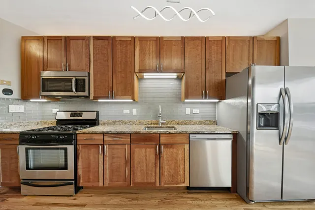 a kitchen with kitchen island granite countertop wooden cabinets and stainless steel appliances