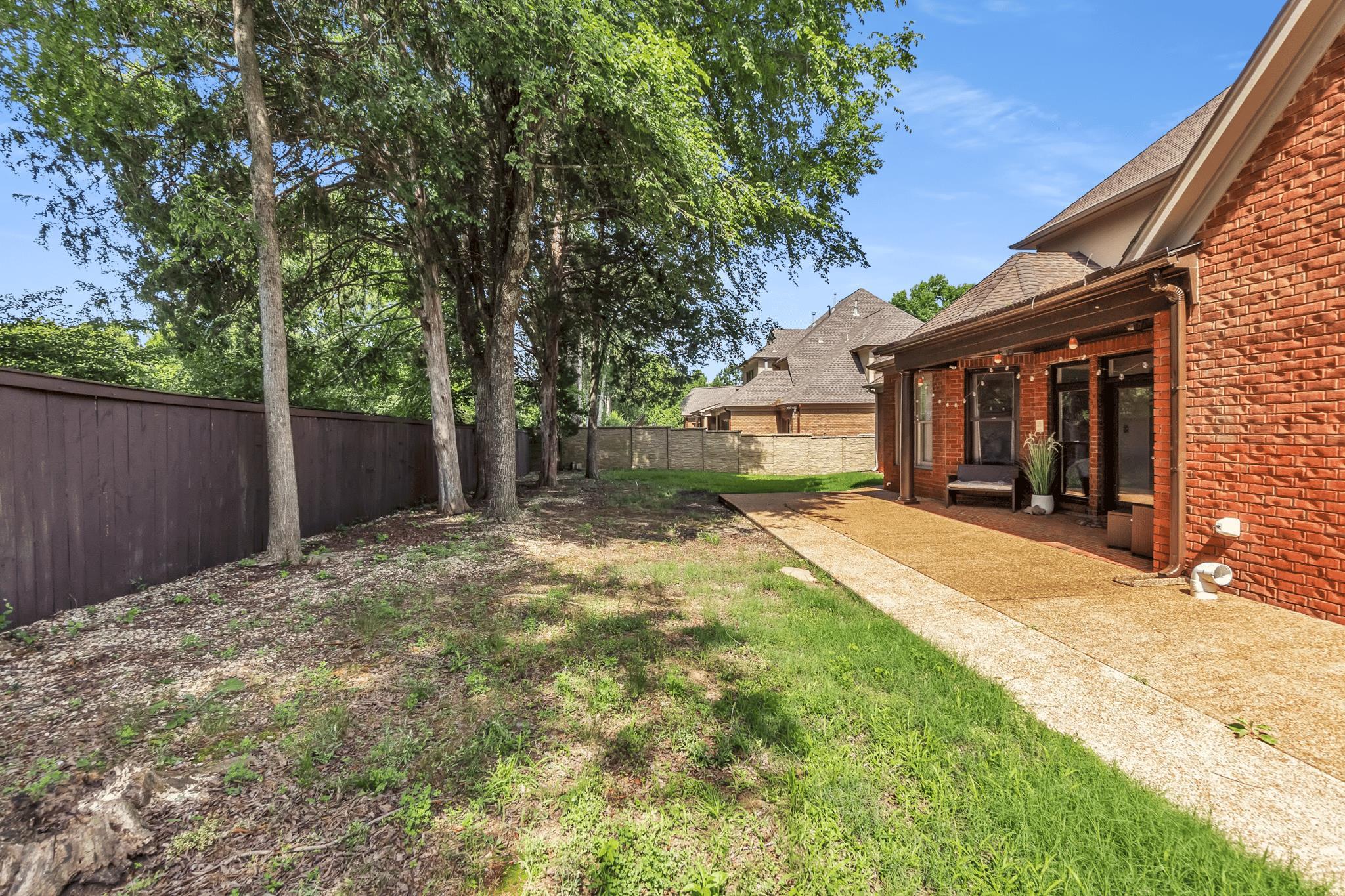 649 Ridge Springs Road Collierville, TN 38017 - Photo 8 of 38 Expansive backyard featuring a red brick exterior, covered patio, gravel patio surface, concrete pathway, and a tall wood fence
