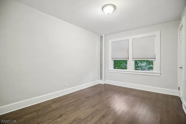 an empty room with wooden floor and window