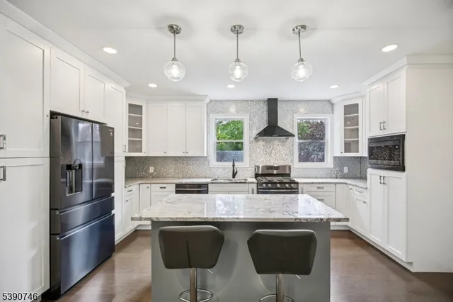 a kitchen with stainless steel appliances granite countertop a refrigerator a stove a sink a dining table and chairs