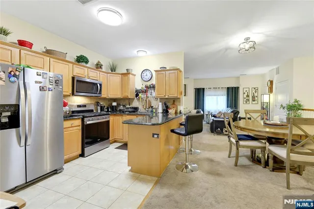 a kitchen with stainless steel appliances kitchen island granite countertop a refrigerator and microwave