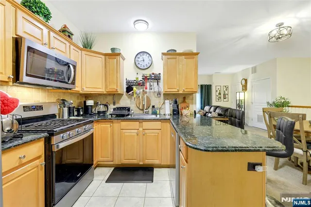 a kitchen with a stove a sink and a granite counter tops with white cabinets