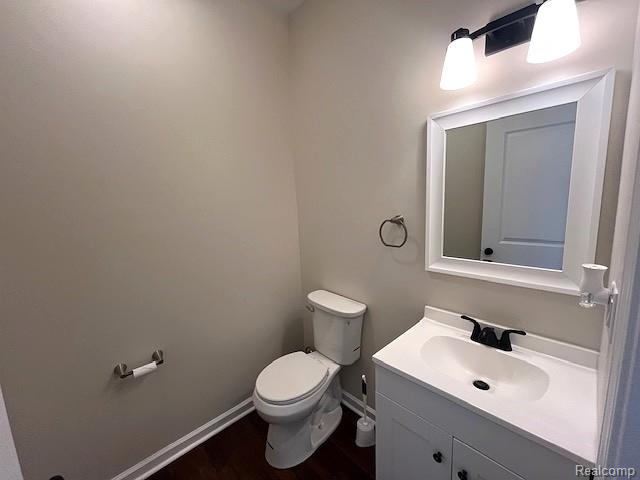 2670 Riley Center Road Memphis, MI 48041 - Photo 12 of 24 Vanity with integrated sink, dark wood-finish flooring, white baseboards, and a wall-mounted light fixture