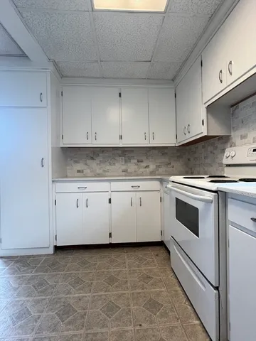 a white kitchen with granite countertop white cabinets and white appliances