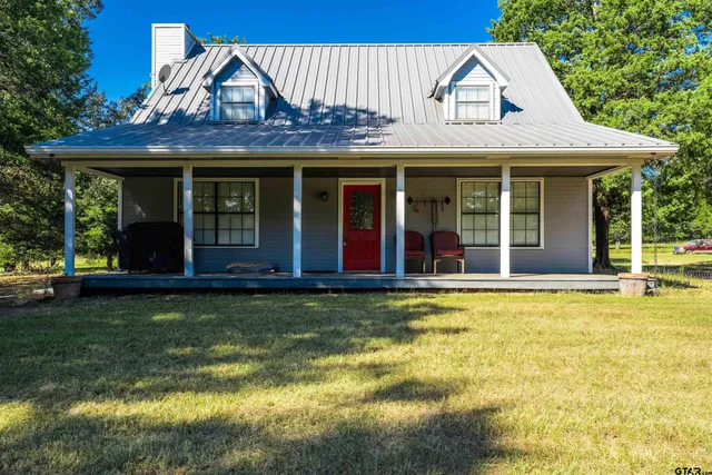 a view of a white house with a large pool and a lawn chairs under an umbrella