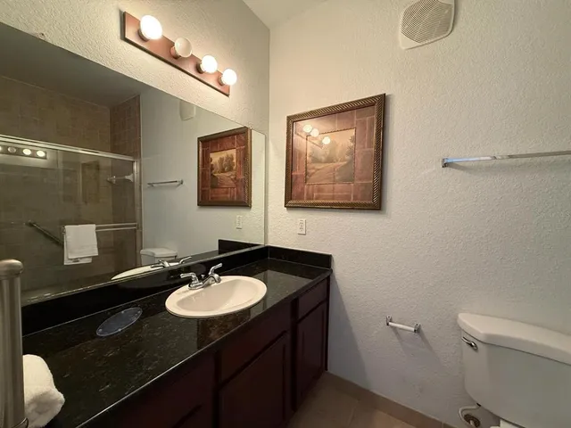 a bathroom with a sink vanity granite and toilet