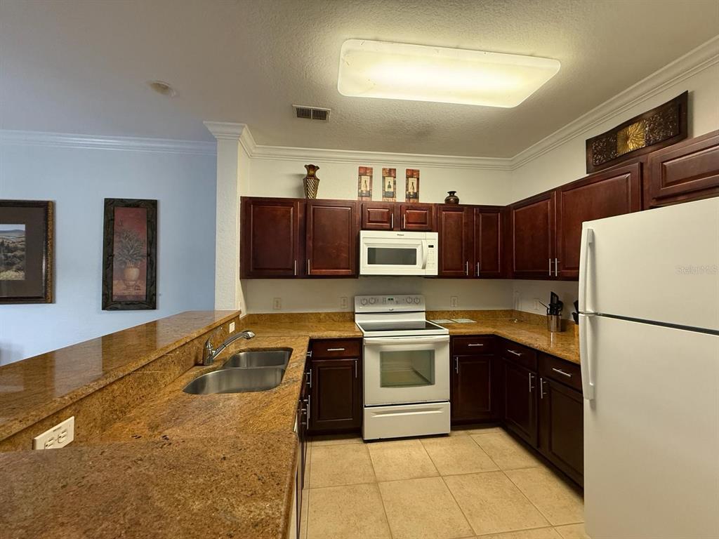 1361 Tuscan Terrace, Unit 7307 Davenport, FL 33896 - Photo 6 of 22 a kitchen with stainless steel appliances granite countertop a sink stove and refrigerator