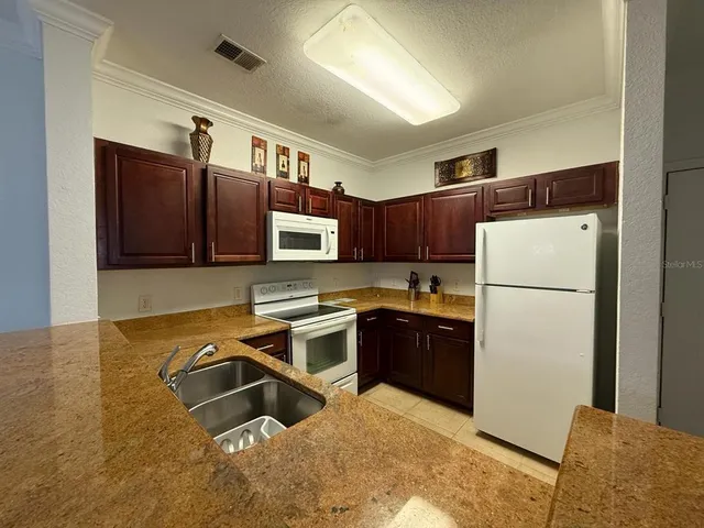 a kitchen with stainless steel appliances granite countertop a refrigerator a stove and a sink with wooden floor
