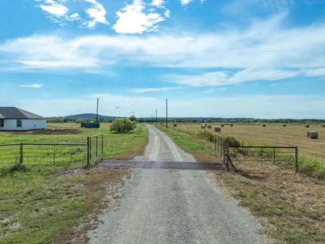 a view of a pathway both side of grassy field with shrub