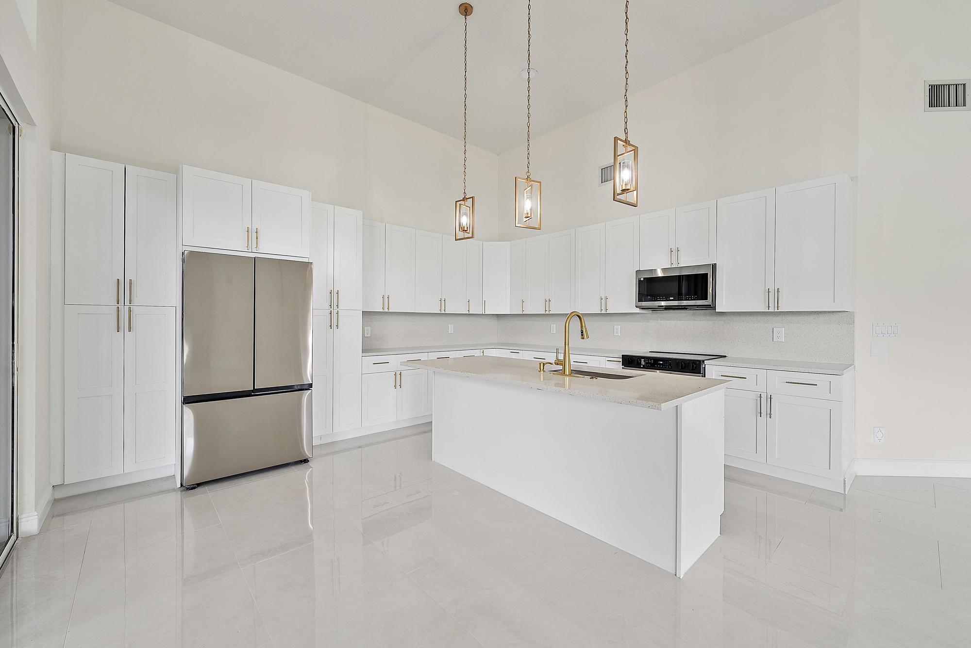 19558 Red Gum Trail Jupiter, FL 33458 - Photo 11 of 34 a kitchen with kitchen island a white cabinets and refrigerator