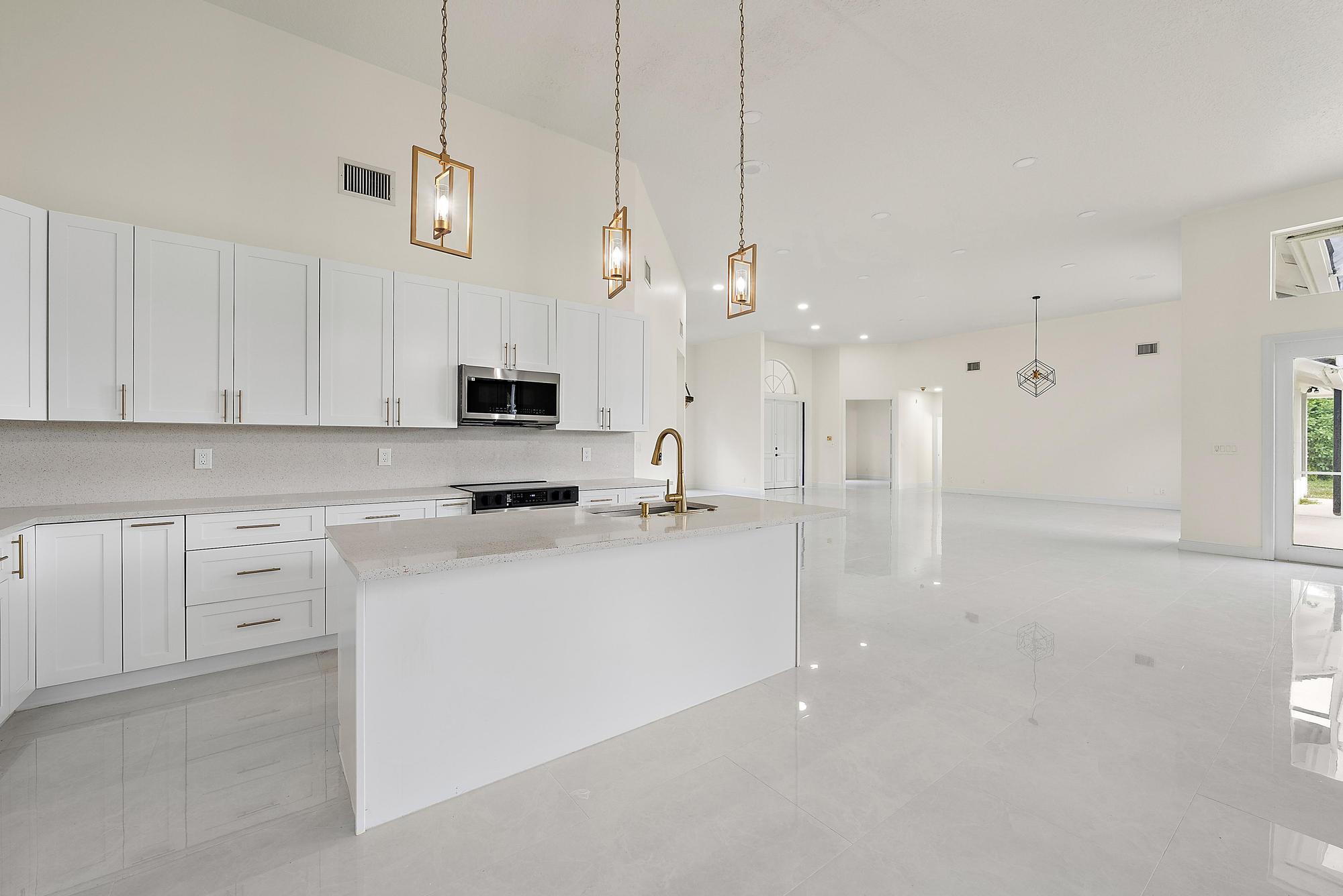 19558 Red Gum Trail Jupiter, FL 33458 - Photo 12 of 34 a kitchen with stainless steel appliances a stove a sink and white cabinets